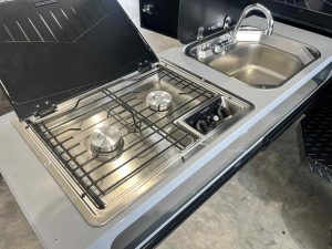 Stainless steel kitchen featuring a sink and Dometic dual burner propane stove for versatile cooking options.