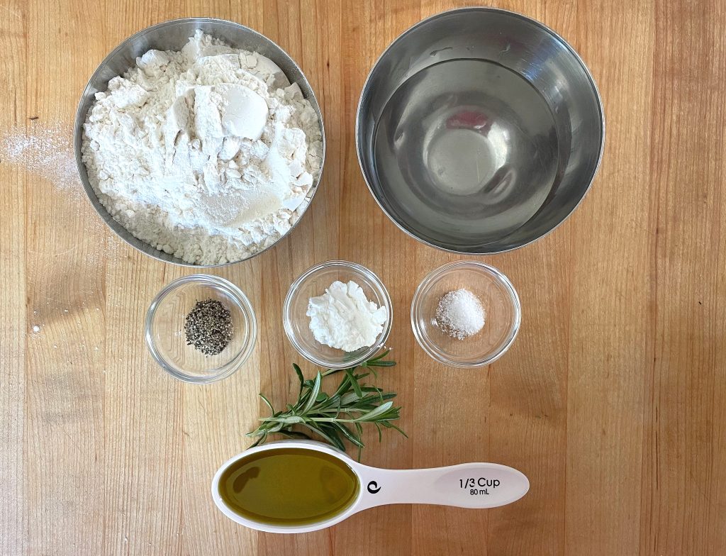 Ingredients for home-made crackers: all-purpose flour, water, salt, baking powder, black pepper, fresh rosemary, and olive oil.