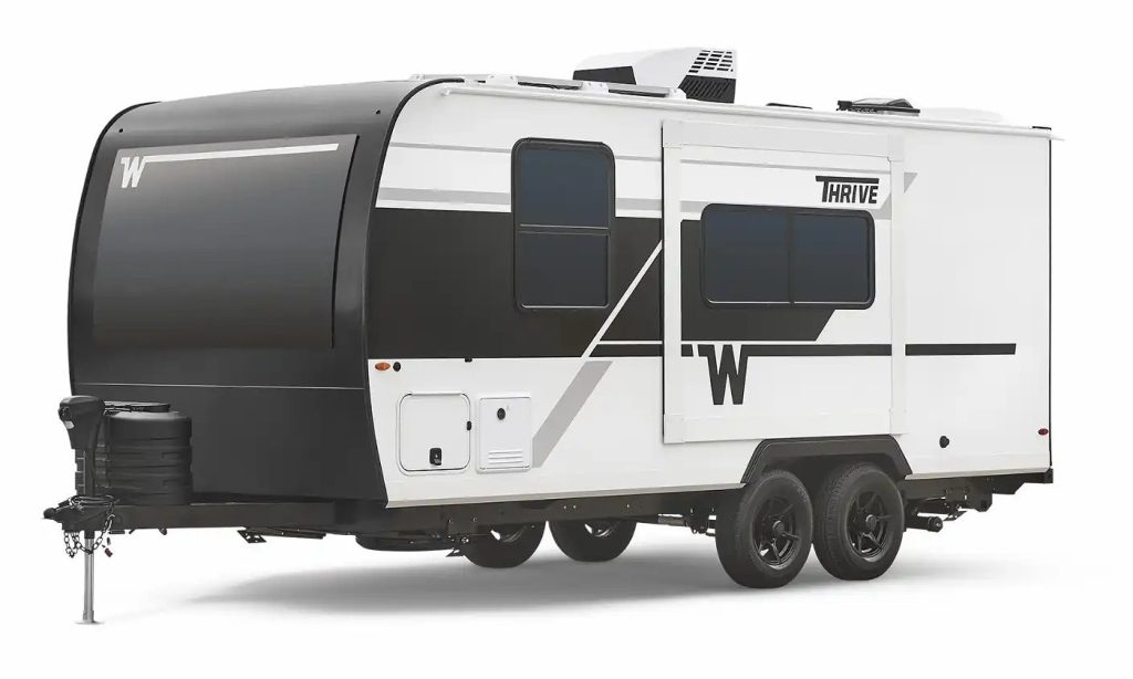 Header Image: g-e1-white-driver-34-thrive-18fbs-26 Change File Name: 2026-Winnebago-Thrive Alt-Text: A modern white and black travel trailer with dual axles and the word “Thrive” displayed near the windows.