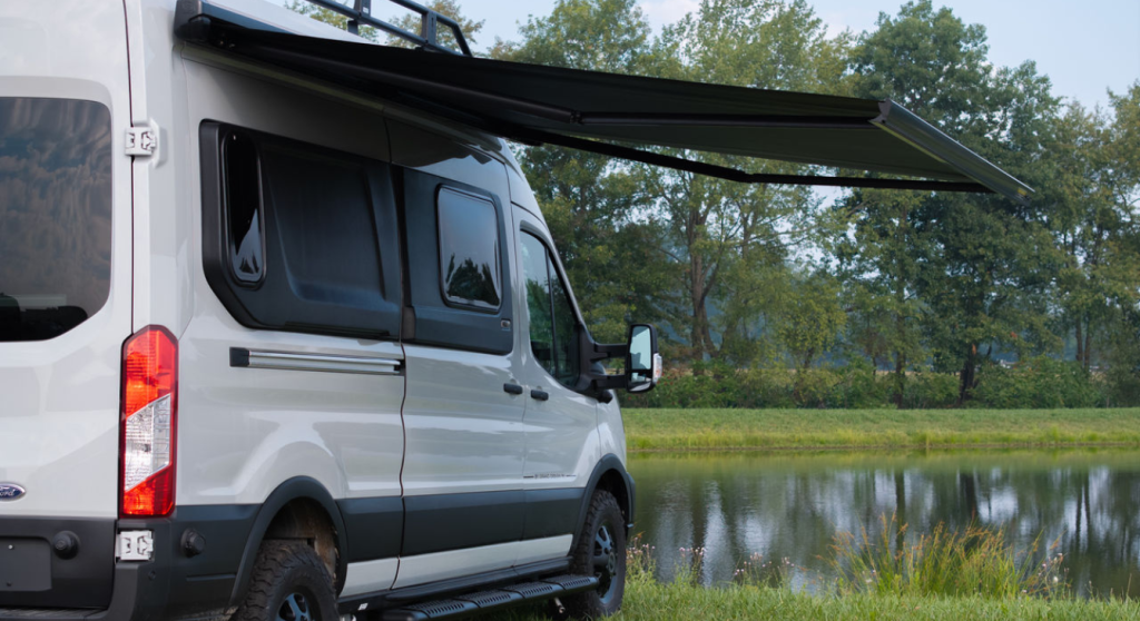 The 2026 Grand Design Lineage Series VT parked near a lake with the awning extended.