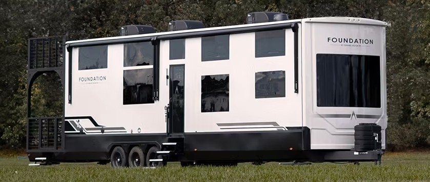 The 2026 Grand Design Foundation 42GD sitting on a grass field next to a forest.