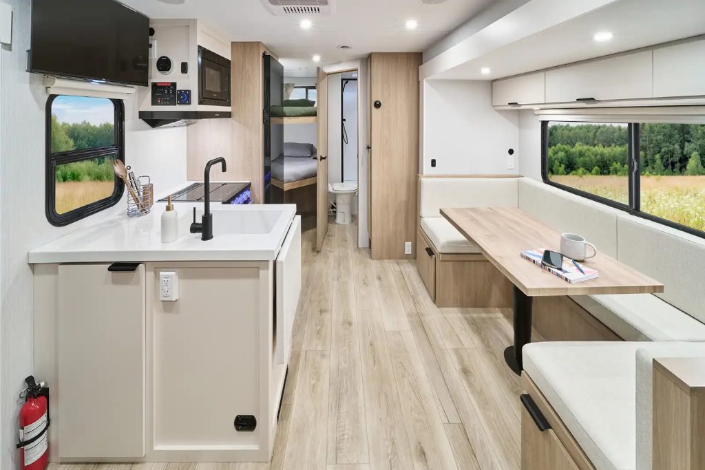 Interior of the 2026 Winnebago Thrive 26FKD travel trailer featuring a spacious front kitchen, panoramic window, queen bed, and modern amenities.