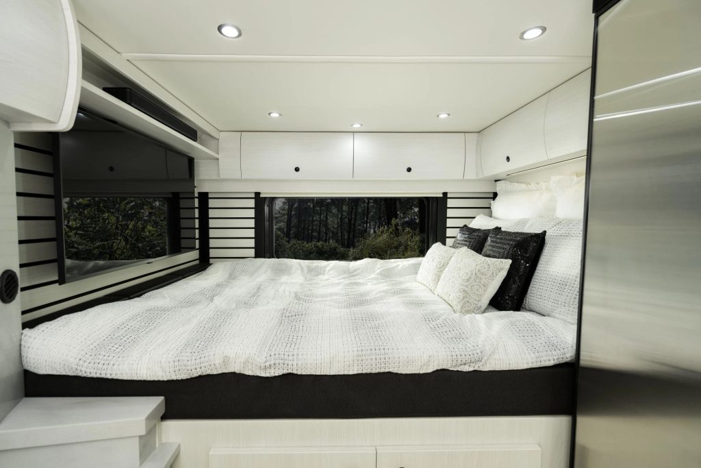 Rear interior view of the 2026 Pleasure-Way Plateau XLRB showing the raised bed and cabinetry.