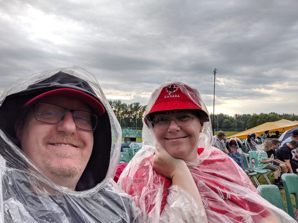 RV travellers wearing ponchos at outdoor camping event in the rain.