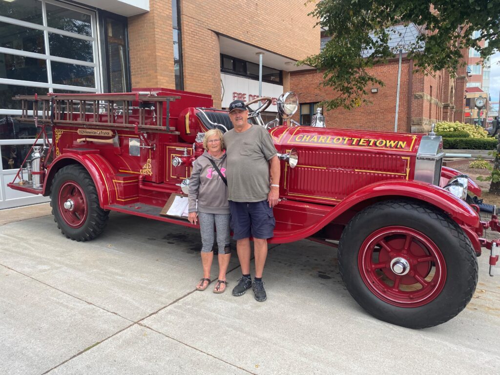 RV travellers standing beside a vintage firetruck during a road trip.