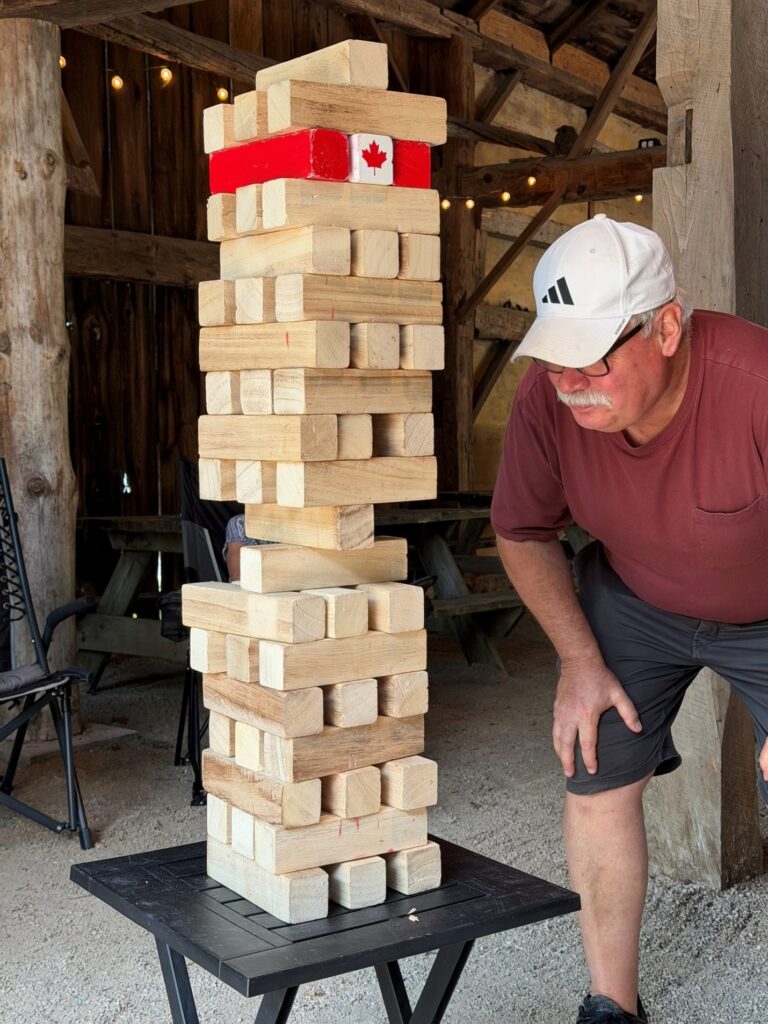 Person playing giant Jenga at a campground pavilion during an Explorer RV Club campout.