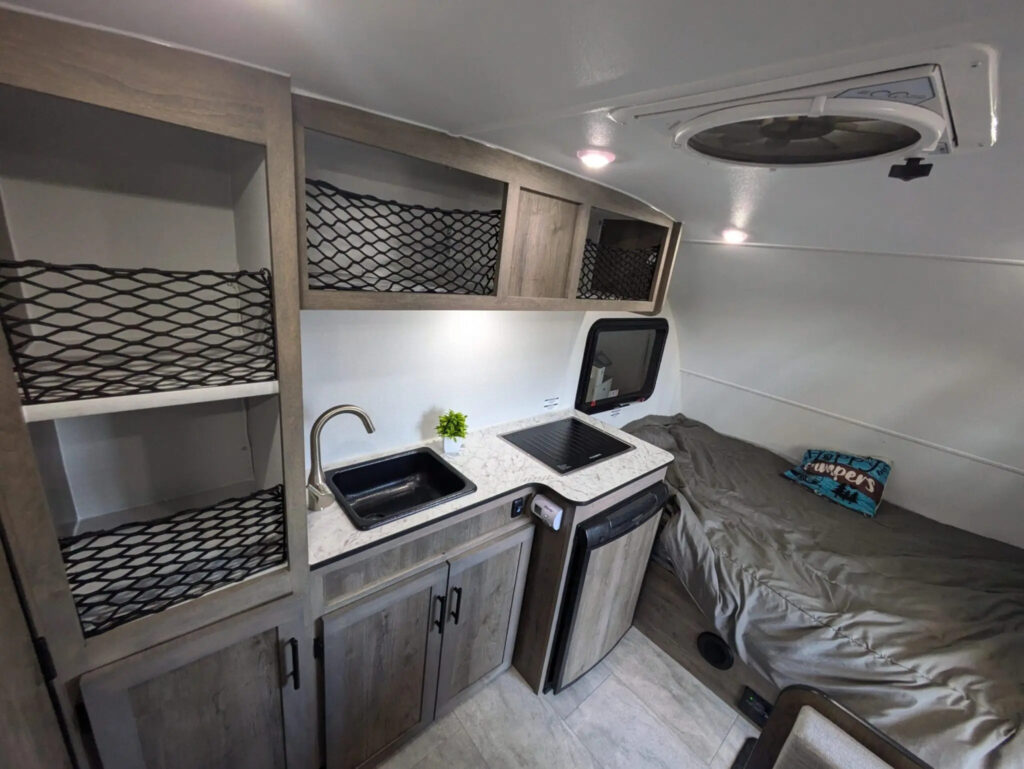 Interior of a Prolite Lounge Eco trailer with a dinette, sofa bed, kitchenette and wood cabinetry.